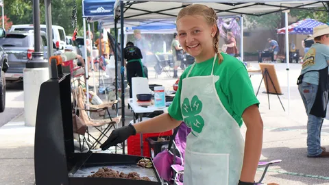 A 4-H member prepares food on a flat-top grill during the Outdoor Cookery competition at the 2026 North Carolina 4-H State Presentation Finals.