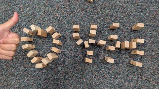 Child's hand giving a thumbs up next to Jenga pieces in the shape of a heart and 4-H.