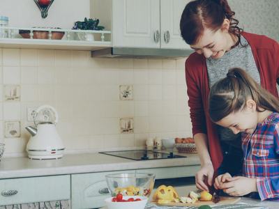 Adult and child preparing food together in a  home kitchen setting