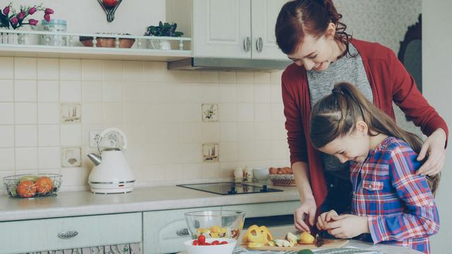 Adult and child preparing food together in a  home kitchen setting